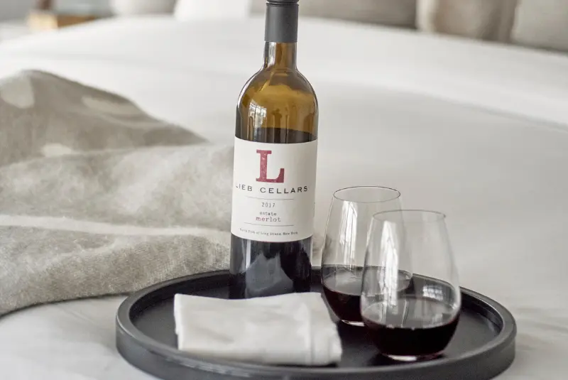 A bottle of red wine on a tray with a glass and napkin, likely a promotional image for a wine brand.