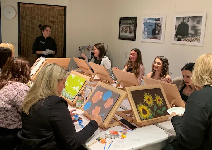 people in a room painting on canvas.