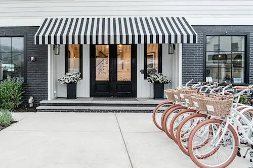 Bicycles in front of a storefront with a black-and-white striped awning and a black door.