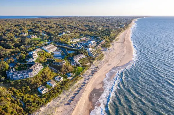 Aerial view of a coastal town with a sandy beach and ocean waves.
