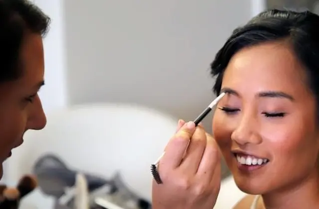A woman having her makeup applied by a professional.